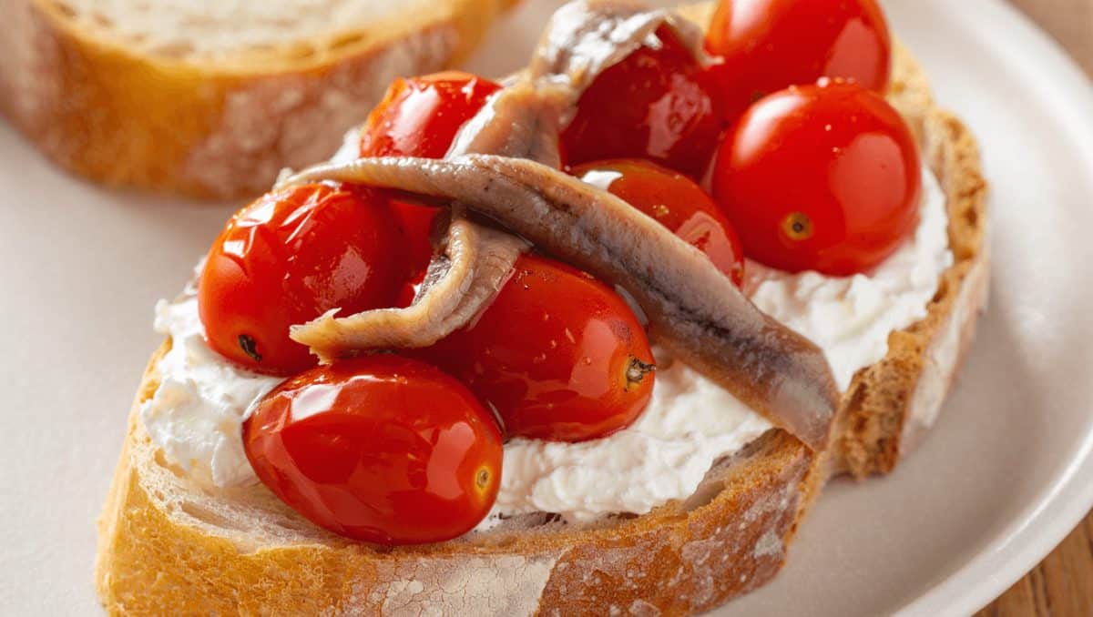 Bocadillo de tomatitos marinados con anchoas y queso ricotta. Receta