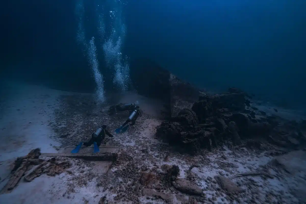 Manos de arqueólogo submarino examinando fragmentos cerámicos en el fondo marino