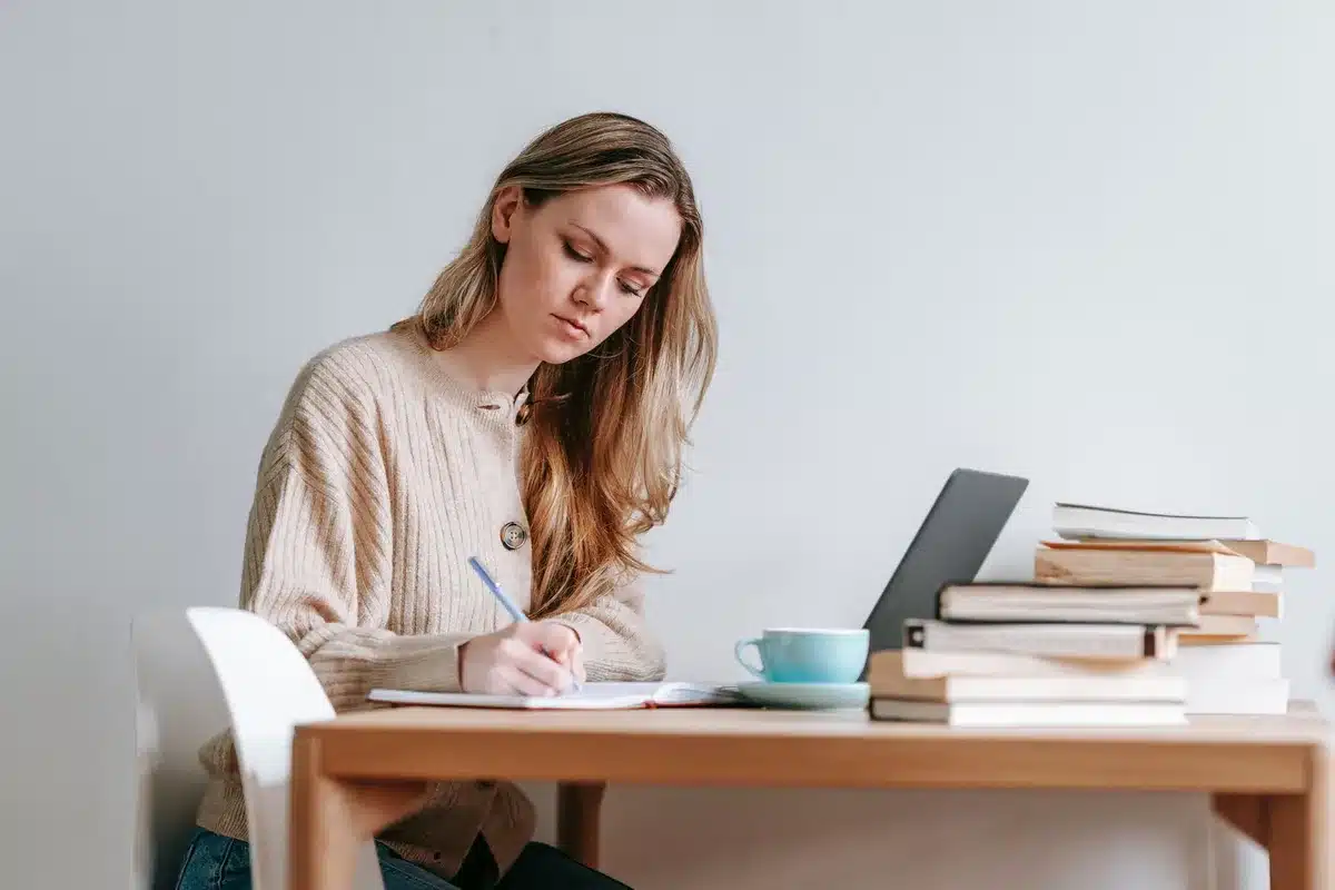 Mujer escribiendo en un escritorio, reflejando el proceso de transformar experiencias dif&iacute;ciles en narrativa.