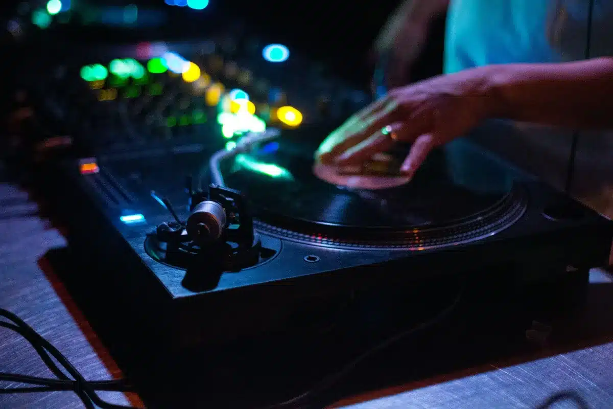 Manos de un DJ manipulando platos y equipo de mezcla en un estudio oscuro