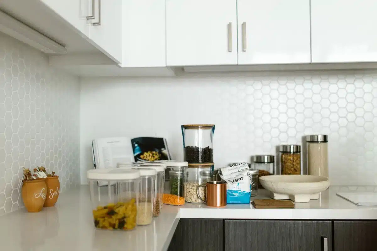 Estantería extensible organizada sobre encimera de cocina con tazas, frascos y pequeños electrodomésticos