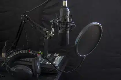 Manos de un técnico junto a un micrófono y guiones en una mesa de radio