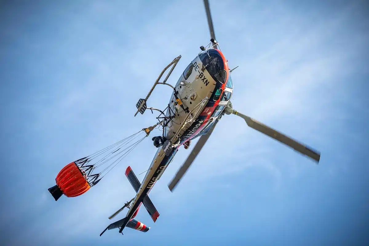 Helicóptero de extinción descargando agua sobre un incendio forestal