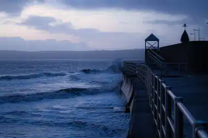 Equipo meteorológico anónimo en la costa con mar agitado y nubes de tormenta
