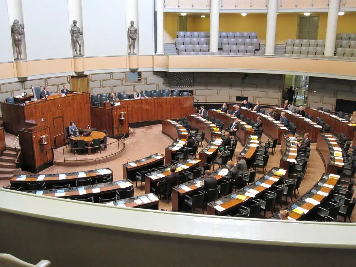 Hemicíclo con parlamentarios en debate y líder hablando desde su escaño