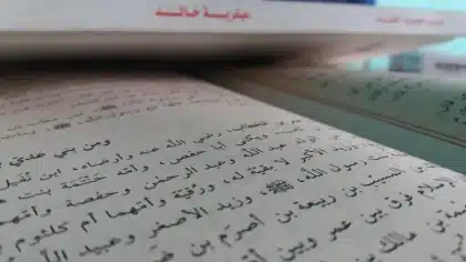 Mano sosteniendo un libro de historia con documentos de archivo de la Guerra Civil española de fondo