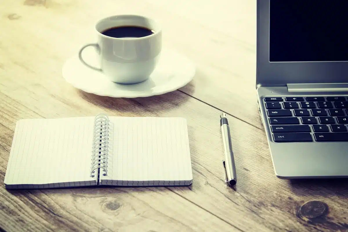 Taza de café humeante sobre escritorio durante la noche, con reloj de fondo