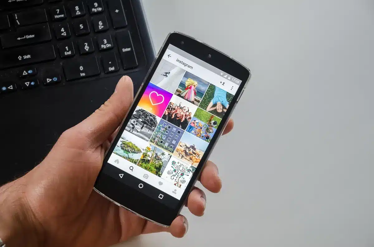 Dos móviles en una mesa de café mostrando feeds de redes sociales y reacciones, manos al fondo