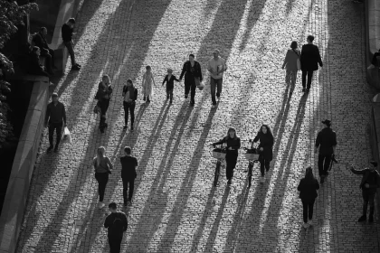 Multitud anónima en una plaza de ciudad con banderas y manos alzadas, vista lejana