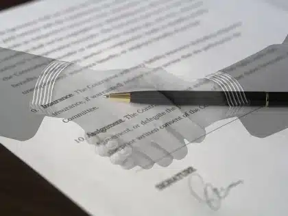 Manos con documentos legales sobre una mesa en una oficina municipal, siluetas al fondo